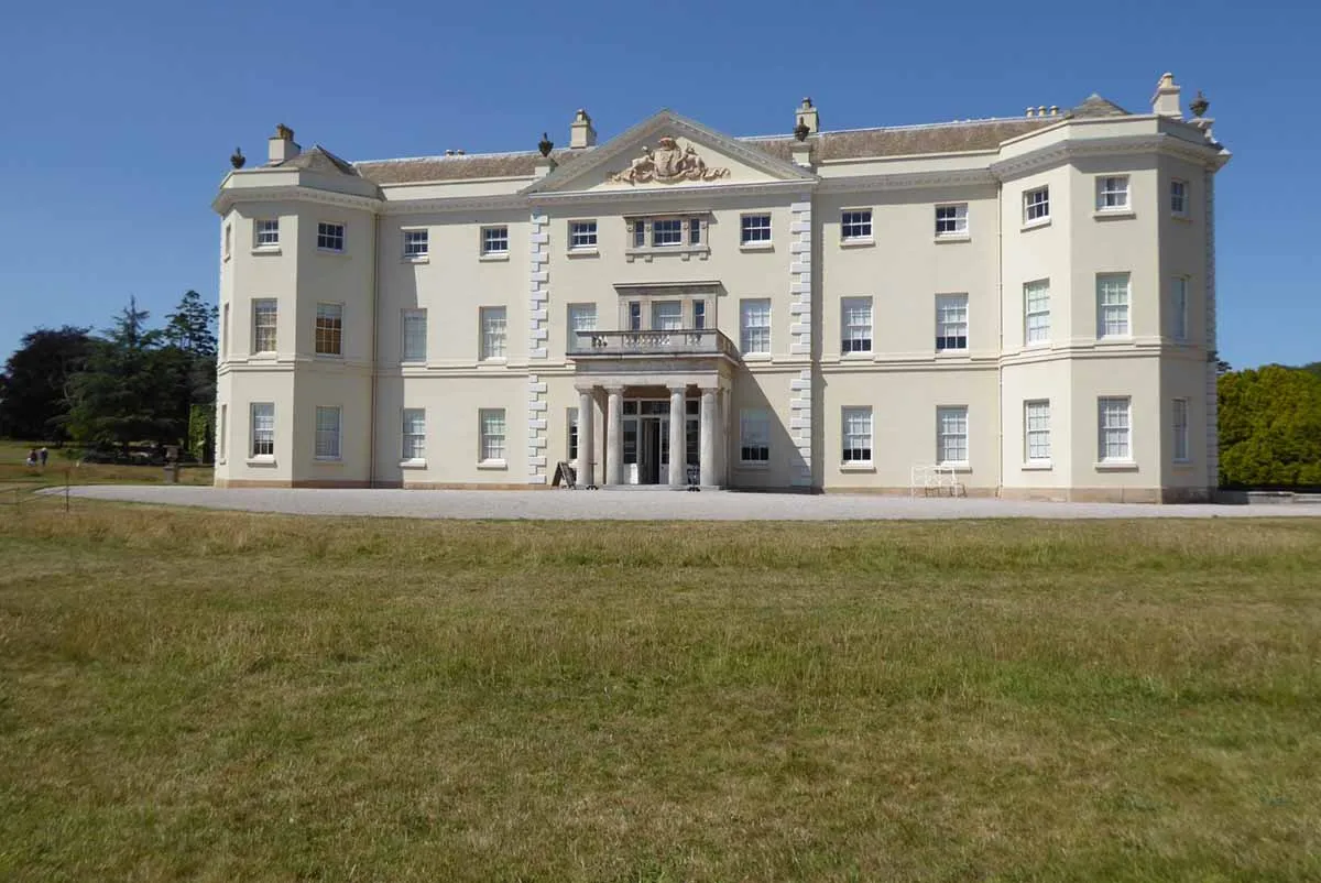 photo showing a beautiful white Georgian house in England, set in a green park.