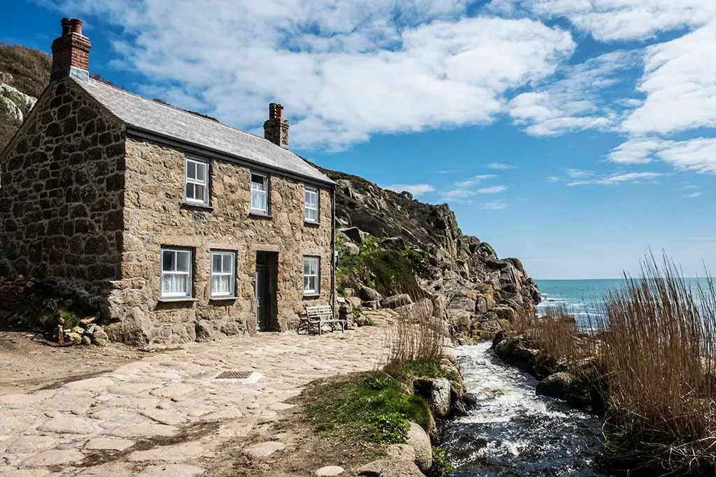Photo showing an example of rural retreats in the UK, with a stone cottage beside the sea.